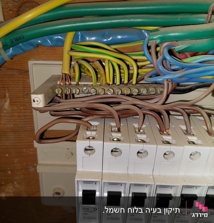 חוטי חשמל צבעוניים מחוברים למפסקי חשמל בלוח חשמל